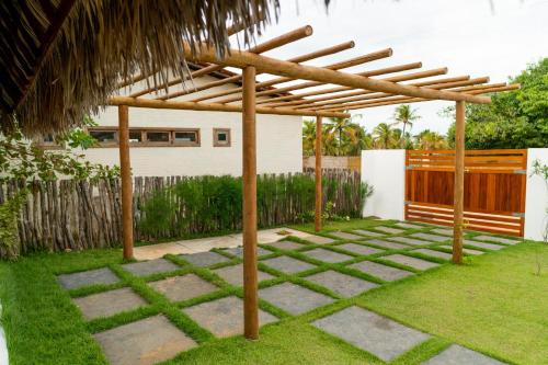 a wooden pergola in a yard with grass at Pousada Coco Cabana in Camocim