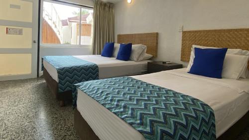 a hotel room with two beds with blue pillows at On Vacation Blue Reef in San Andrés