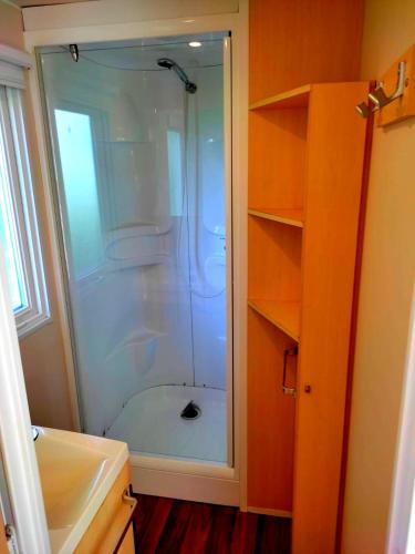 une douche avec une porte vitrée dans une salle de bain dans l'établissement Mobil Home près de l'entrée et de la piscine, à Saint-Chéron