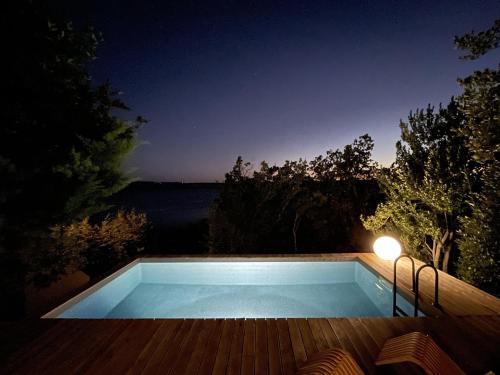 a swimming pool at night with a view of the water at AB61 Tiny Design House for Two in Jadranovo