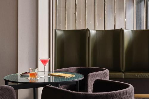 a table with a glass of wine and chairs at Melbourne Marriott Hotel Docklands in Melbourne
