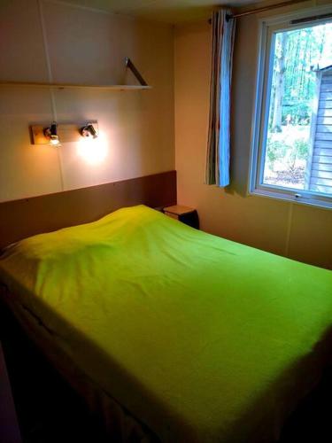 - un lit vert dans une chambre avec fenêtre dans l'établissement Mobil-home dans la forêt haute et tranquille, à Saint-Chéron