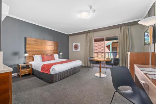 Quality Hotel Dickson في كانبرا: غرفة الفندق بسرير وطاولة