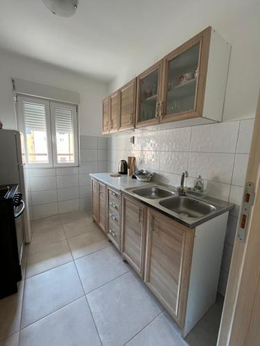 - une cuisine avec des placards en bois et un évier dans l'établissement Orlando apartman, à Kotor