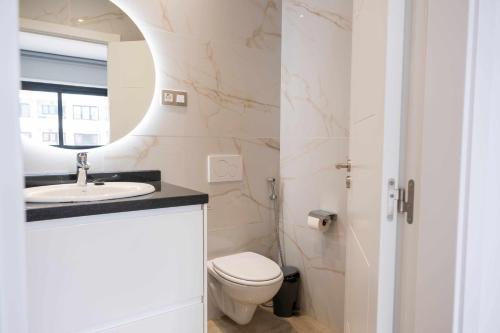 Un baño con inodoro, lavabo y espejo. en Luxury Apartments Sea Sabi con garaje, en Corralejo