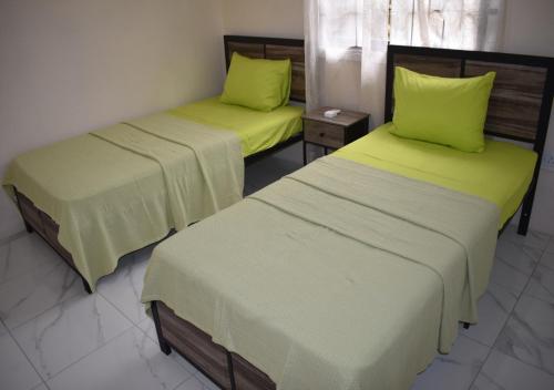 two beds with green sheets in a room at Villa Cherry in Gros Islet