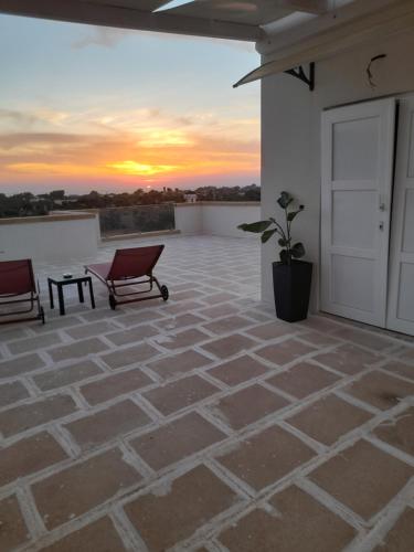 a patio with two chairs and a sunset in the background at B&B MARRELLA in Capilungo