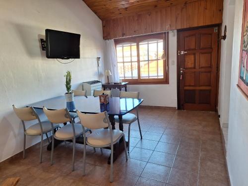 uma sala de jantar com uma mesa e cadeiras e uma televisão em Casa Bis em Villa Gesell