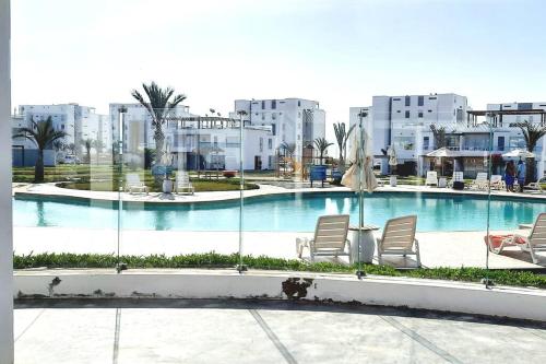 Una piscina con sillas y edificios al fondo. en Condominio Nautico Paracas, en Pisco