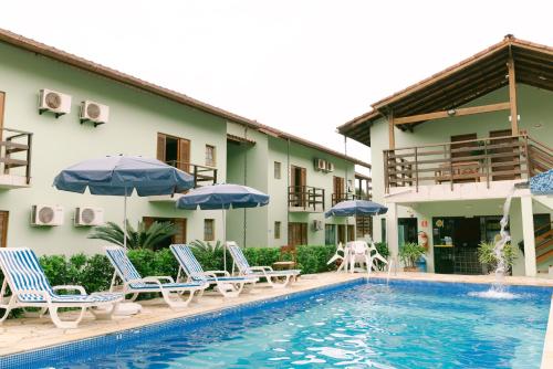a hotel with a swimming pool with chairs and umbrellas at Hotel Kiribati Maresias in Maresias