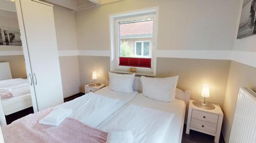 ein kleines Schlafzimmer mit einem weißen Bett und einem Fenster in der Unterkunft Feriendorf Südstrand Haus 13 in Pelzerhaken