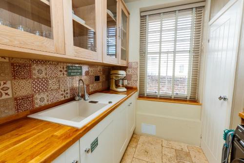 a kitchen with a sink and wooden counters and windows at Westholme Lodge in Minehead