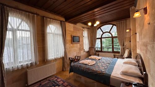 a bedroom with a bed in a room with windows at Akuzun Stone Hotel in Urgup