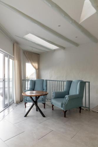 two chairs and a table in a room with a balcony at Capri Sands Luxury Guest House in Capri Village