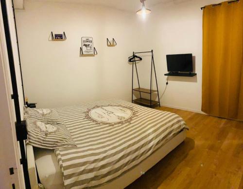 a room with a bed and a television in it at La fermette: Logis indépendant proche d'Arras sur cours au carré in Achicourt