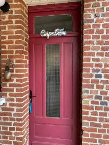 a purple door on a brick building with a sign on it at La fermette: Logis indépendant proche d'Arras sur cours au carré in Achicourt