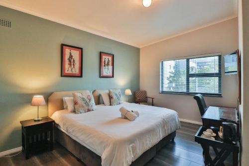 a bedroom with a large white bed with two windows at Spring Tide Inn by CTHA in Cape Town