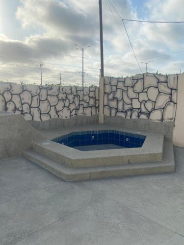 una pared de piedra con una pequeña piscina frente a ella en Carlos Espinoza Larrea , Atras de Agua pen, en Salinas