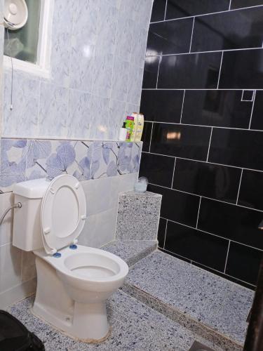 a bathroom with a white toilet and black tiles at Petra Anas House in Wadi Musa