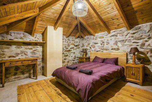 1 dormitorio con cama y pared de piedra en Подковите en Karlovo
