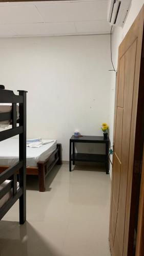 Zimmer mit 2 Betten, einem Tisch und einer Tür in der Unterkunft Habitaciones Mónaco in Coveñas