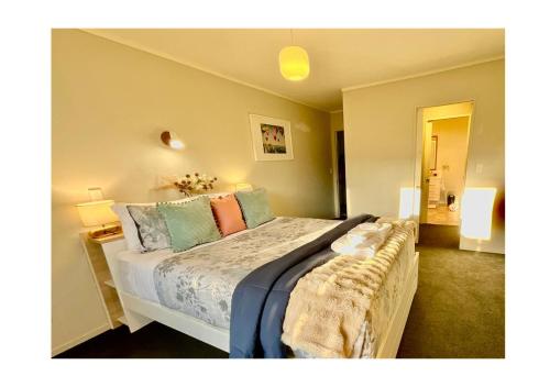 a bedroom with a large bed with colorful pillows at Free-Range On Papmoa Beach in Tauranga
