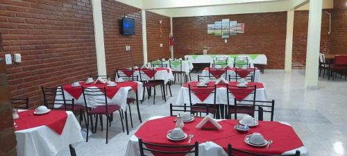 uma sala de jantar com mesas e cadeiras vermelhas e brancas em Hotel Sol em Termas de Rio Hondo