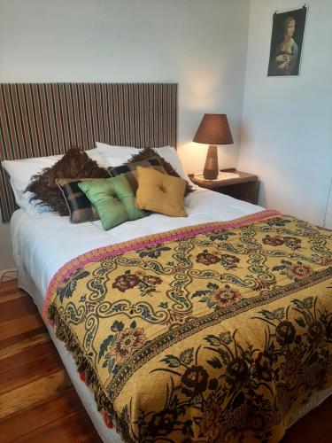 Una cama con una manta colorida y almohadas. en Redwood en Hikutaia