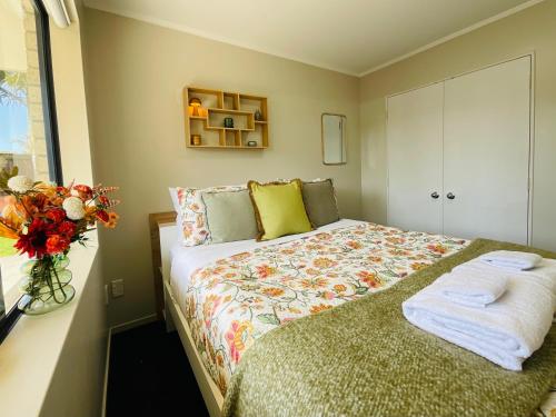 1 dormitorio con 1 cama y un jarrón de flores en Free-Range On Papmoa Beach en Tauranga