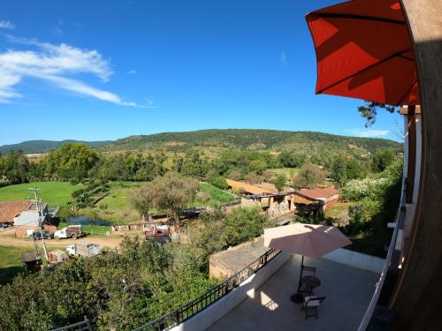 einen Balkon mit Sonnenschirm und Talblick in der Unterkunft La Toscanía Tapalpa Resort & Agroturismo in Tapalpa