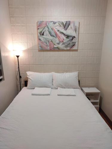 a large white bed with two pillows on it at Helena's Apartelle in Bulakan