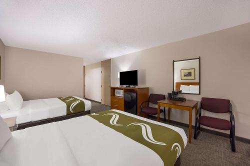 a hotel room with two beds and a desk at Quality Inn & Suites Canon City in Canon City
