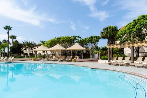una piscina en un complejo con sillas y sombrillas en Hilton Santa Barbara Beachfront Resort, en Santa Bárbara