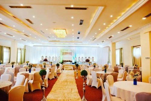 um grande salão de banquetes com mesas e cadeiras brancas em Golden Addis Hotel em Addis Ababa