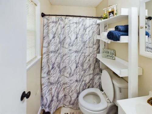 uma casa de banho com um WC e uma cortina de chuveiro em Pine Forest Zen Cottage - 10 Min to Fort Bragg em Fayetteville