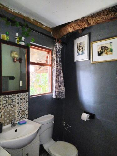 a bathroom with a toilet and a sink and a window at Eden by the sea in Port Shepstone