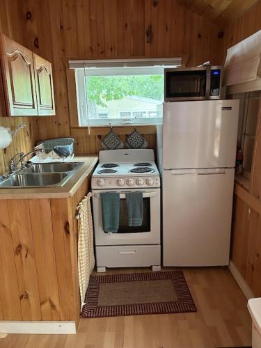 La cuisine est équipée d'une cuisinière blanche et d'un réfrigérateur. dans l'établissement Carry Bay Cottage #1, à North Hero