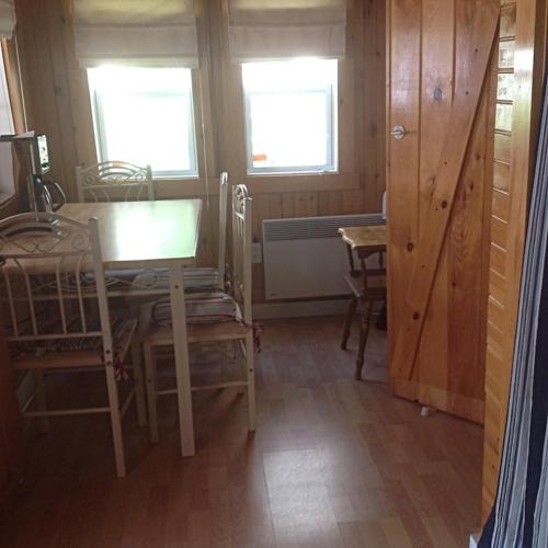 a dining room with a table and chairs and two windows at Carry Bay Cottage #1 in North Hero