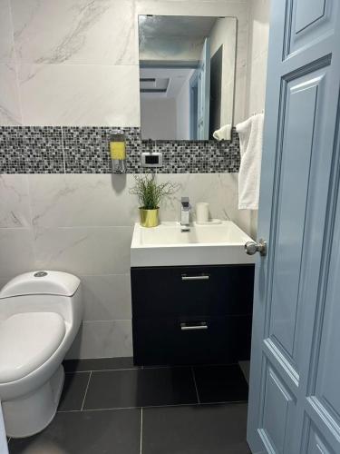 a bathroom with a sink and a toilet and a mirror at Villa Marbella by Potenza Rentals in Santo Domingo