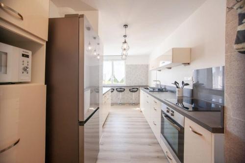 une cuisine avec des placards blancs et un long couloir dans l'établissement Sablier T4 parking dans une residence securisee, à Marseille