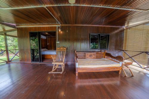 sypialnia z łóżkiem i 2 krzesłami na drewnianej podłodze w obiekcie The River Village Retreat Kiulu w mieście Tamparuli