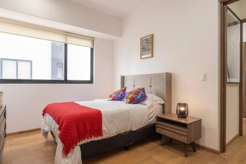 ein Schlafzimmer mit einem Bett mit einer roten Decke und einem Fenster in der Unterkunft Lovely 3-bedroom with pool in La Roma Norte in Mexiko-Stadt