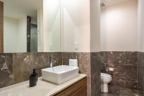 ein Badezimmer mit einem weißen Waschbecken und einem WC in der Unterkunft Lovely 3-bedroom with pool in La Roma Norte in Mexiko-Stadt