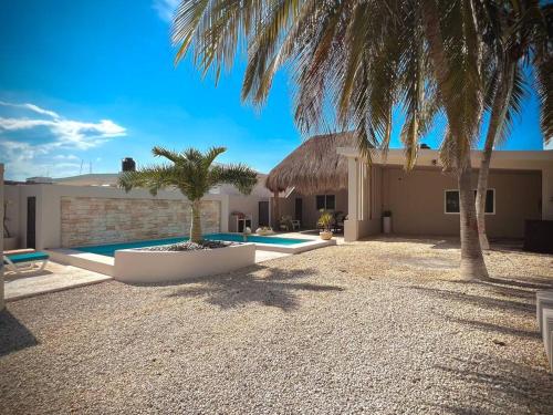 a house with a palm tree and a swimming pool at Beach Bliss Bungalow - Amazing pool in Chelem