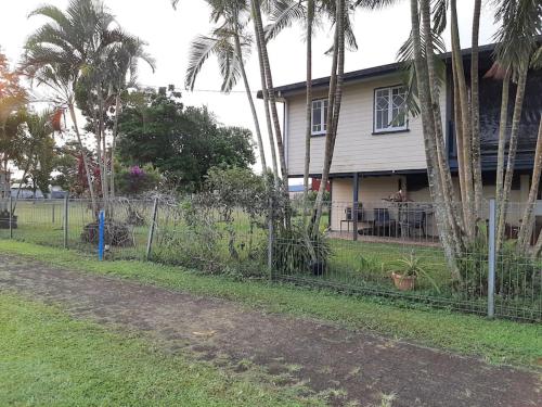 a fence in front of a house with palm trees at Wangan Tropical Getaway 