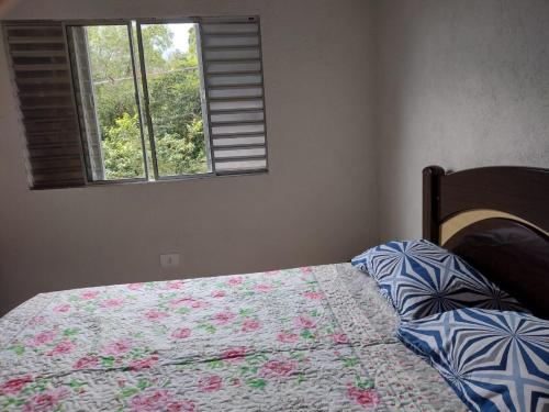 a bedroom with a bed with a quilt and a window at Casa de Praia Ubatuba in Ubatuba