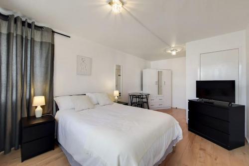 a bedroom with a white bed and a flat screen tv at Regent's Park Apartment in London