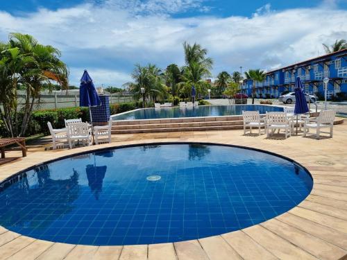 uma piscina no resort com cadeiras e uma mesa em Golden Dolphin Residence em Taperapuan perto Axé Moi em Porto Seguro