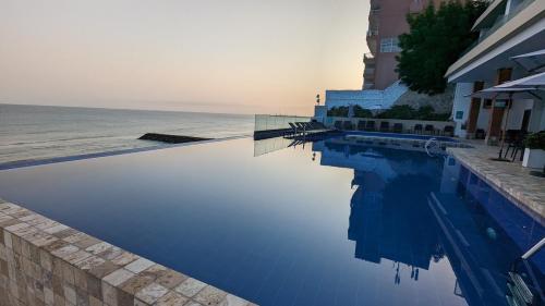 a swimming pool next to the ocean and a building at Departamento vista al mar en Manta Poseidon in Manta