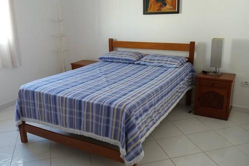 a bed with a blue and white striped comforter in a bedroom at Excelente casa em condomínio fechado em Juquehy. 2 suítes, ar, piscina comum. in São Sebastião